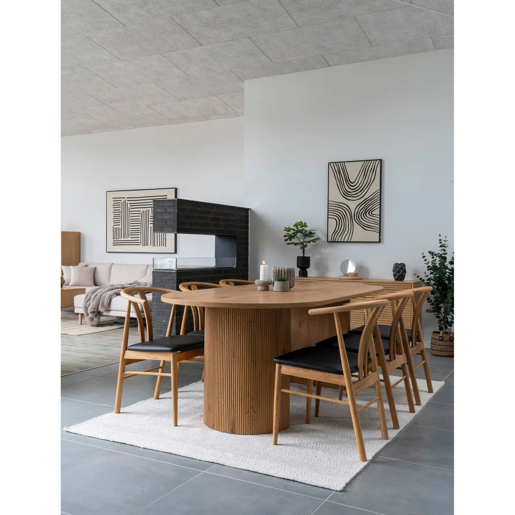 Table ovale en bois clair avec base cannelée et chaises cuir noir