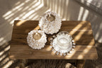 Porte-bougie floral blanc en coquillages sur table bois rustique