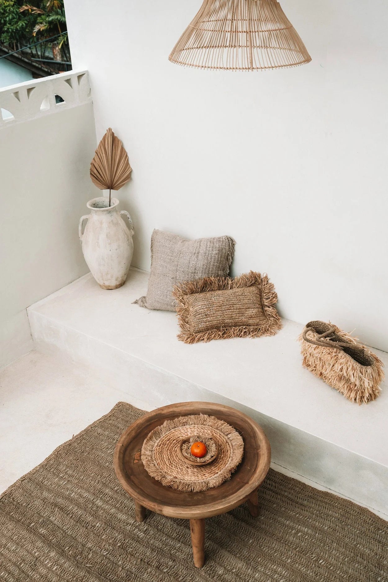 Table basse rond en raphia et herbe de mer avec placemat tressé et fruit orange