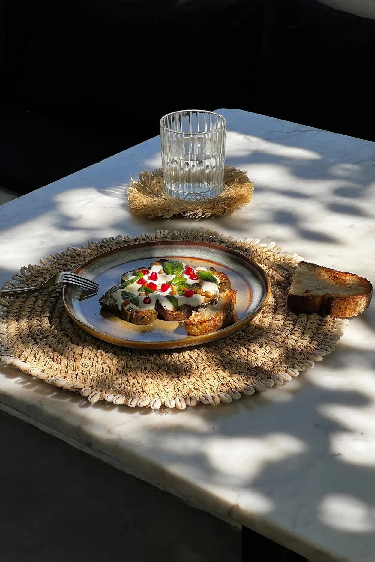 Toast avec crème, feuilles vertes et ingrédients rouges sur un set de table en raphia naturel