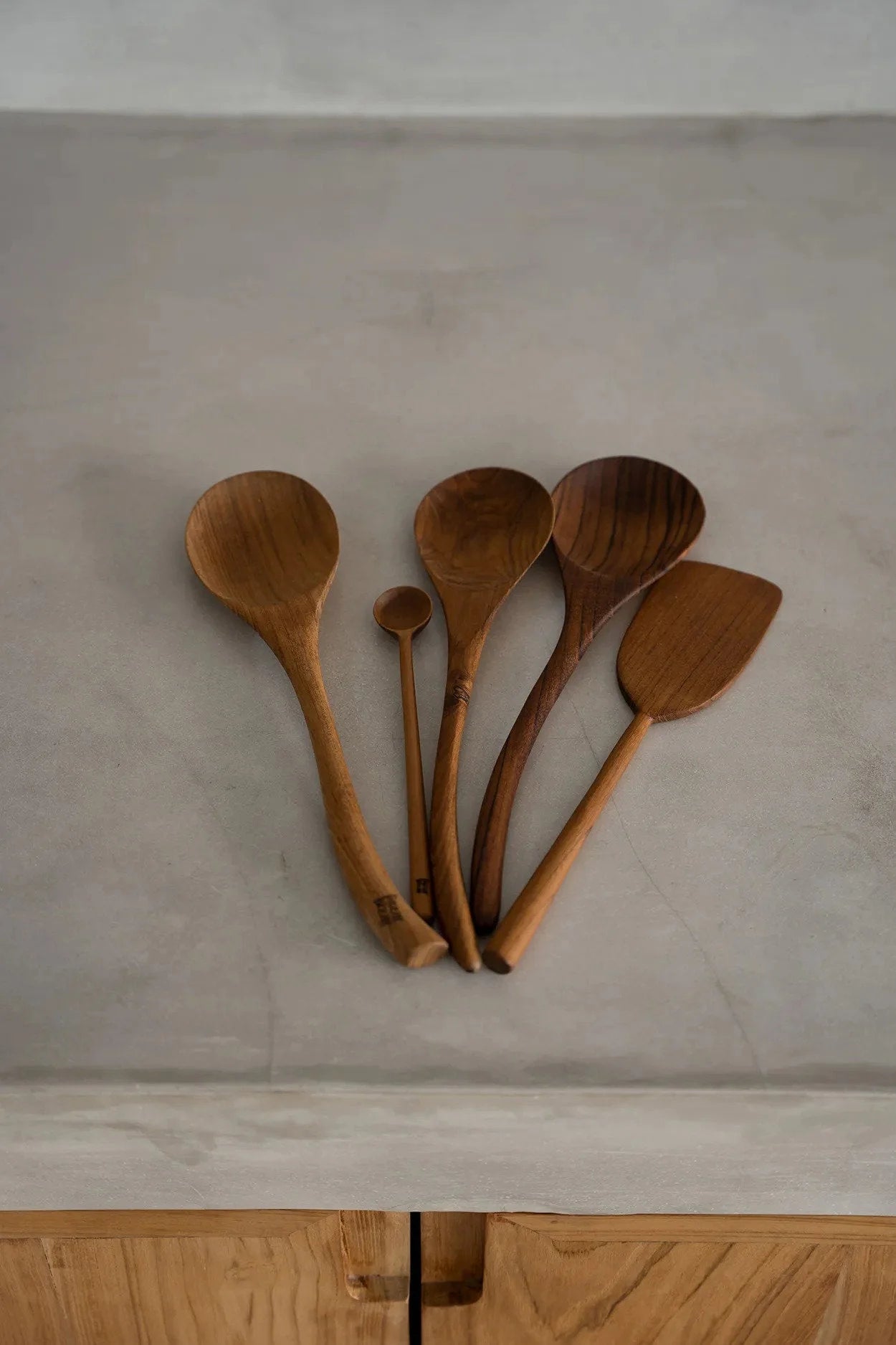 Collection de cinq ustensiles de cuisine en bois naturel, incluant une spatule en racine de teck de 28 cm