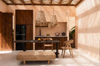 Espace repas avec table en bois foncé, banquette en tissé clair et chaises en bois clair
