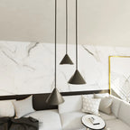 Trois suspensions coniques en métal noir mat, H100 cm, contre mur marbre blanc