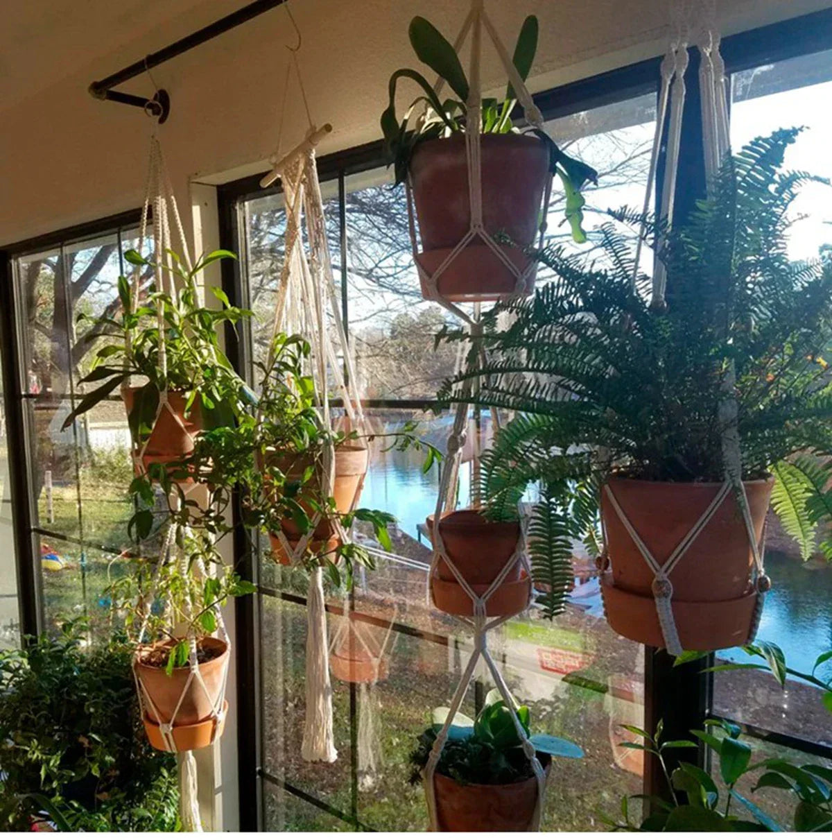 Suspension plante en macramé et perles avec plantes en pot suspendues dans une pièce lumineuse