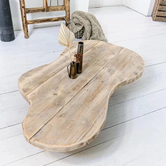 Table basse en bois recyclé avec un design organique, dans un salon lumineux et moderne.