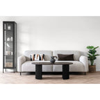 Canapé en tissu gris clair texturé, pieds cylindriques noirs, coussins géométriques