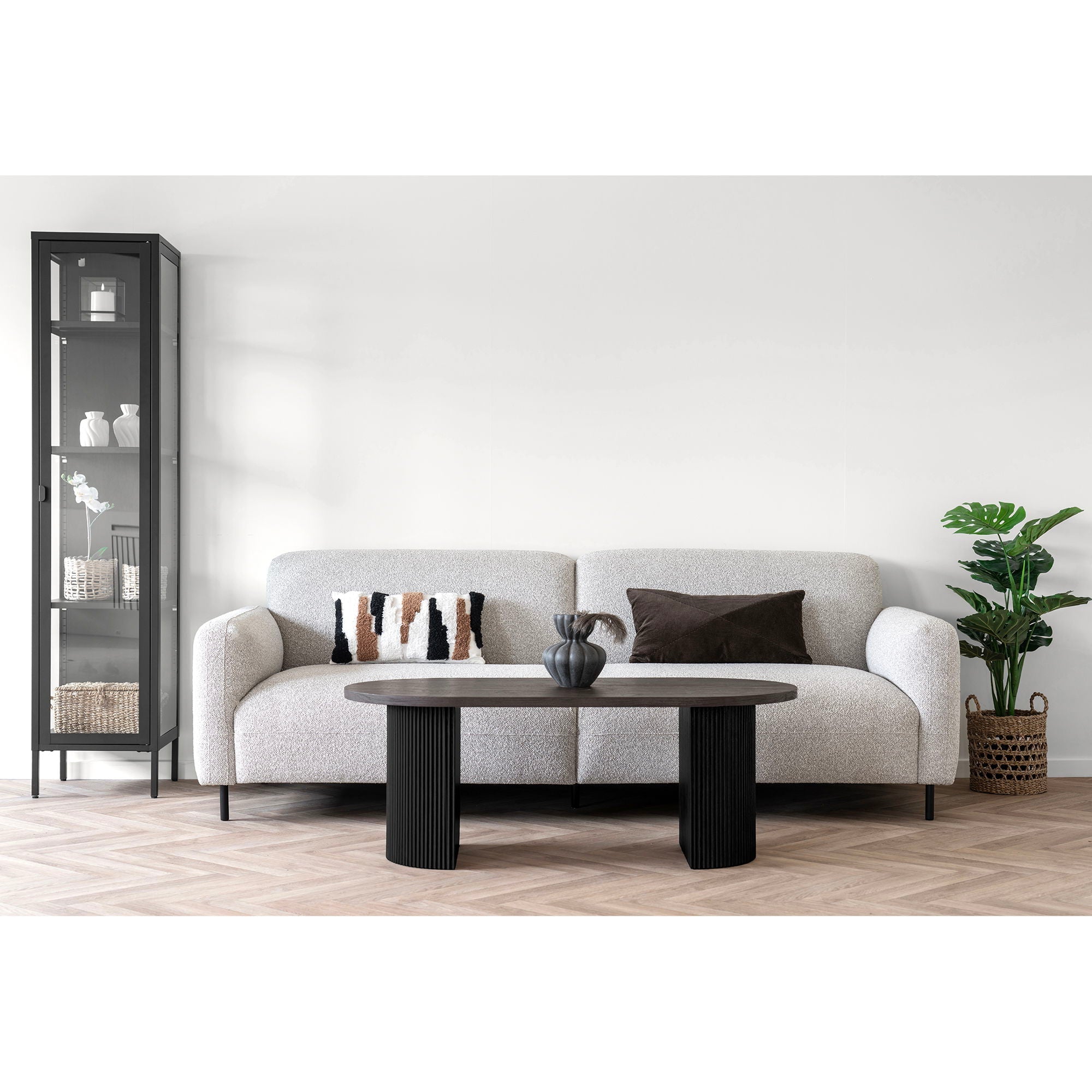 Canapé en tissu gris clair texturé, pieds cylindriques noirs, coussins géométriques