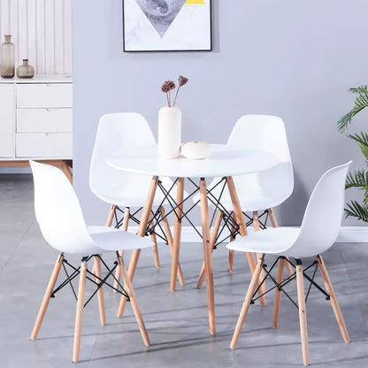 Table ronde blanche de cuisine en bois accompagnée de chaises blanches assorties, ambiance lumineuse et moderne.