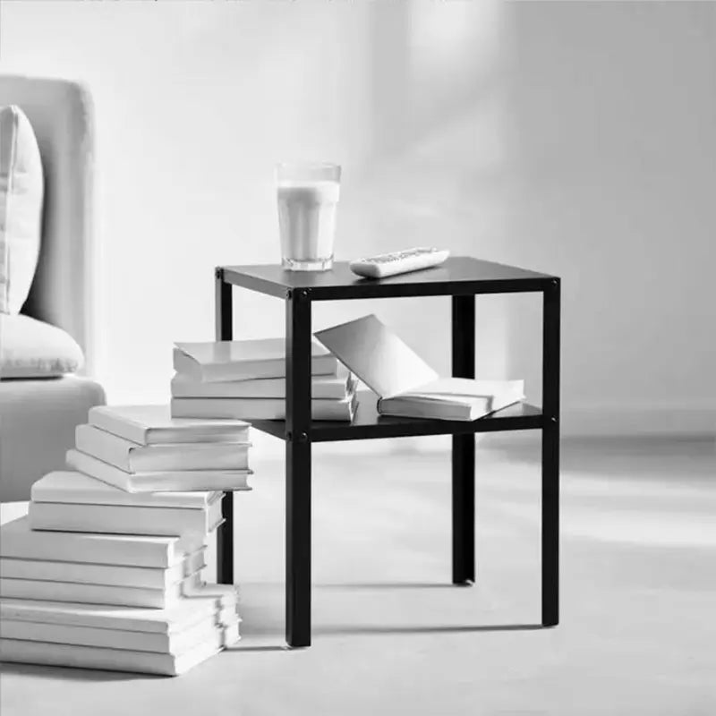 Table de chevet en métal noir décorée avec des livres, un verre et des objets design.