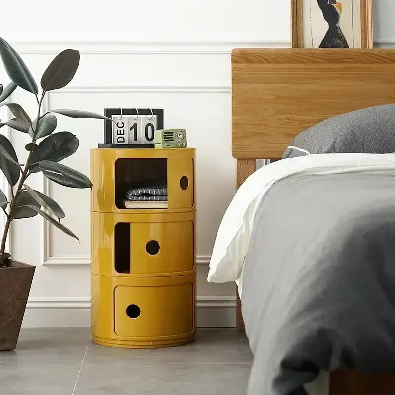 Table de chevet minimaliste jaune avec 3 tiroirs, placée dans une chambre moderne.
