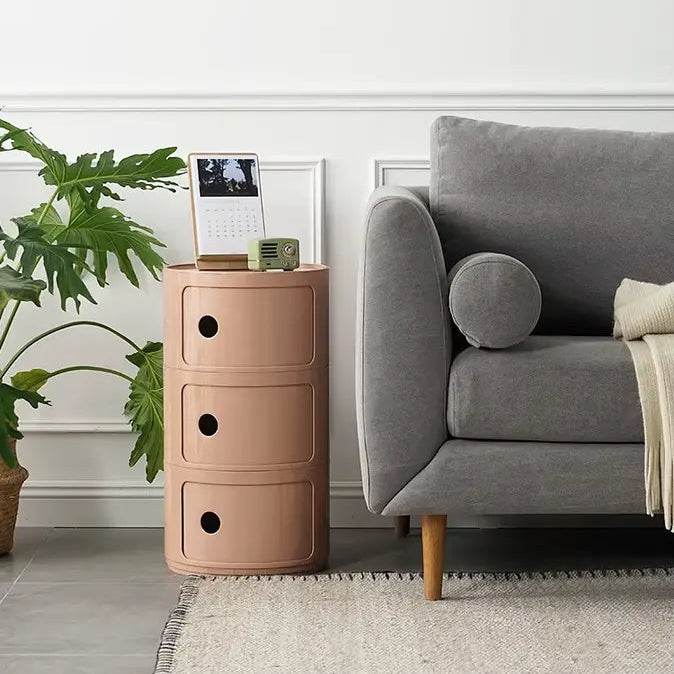 Table de chevet minimaliste beige à 3 tiroirs, utilisée comme meuble d'appoint dans un salon moderne.