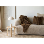 Canapé beige texturé avec plaid marron en fausse fourrure et coussin assorti
