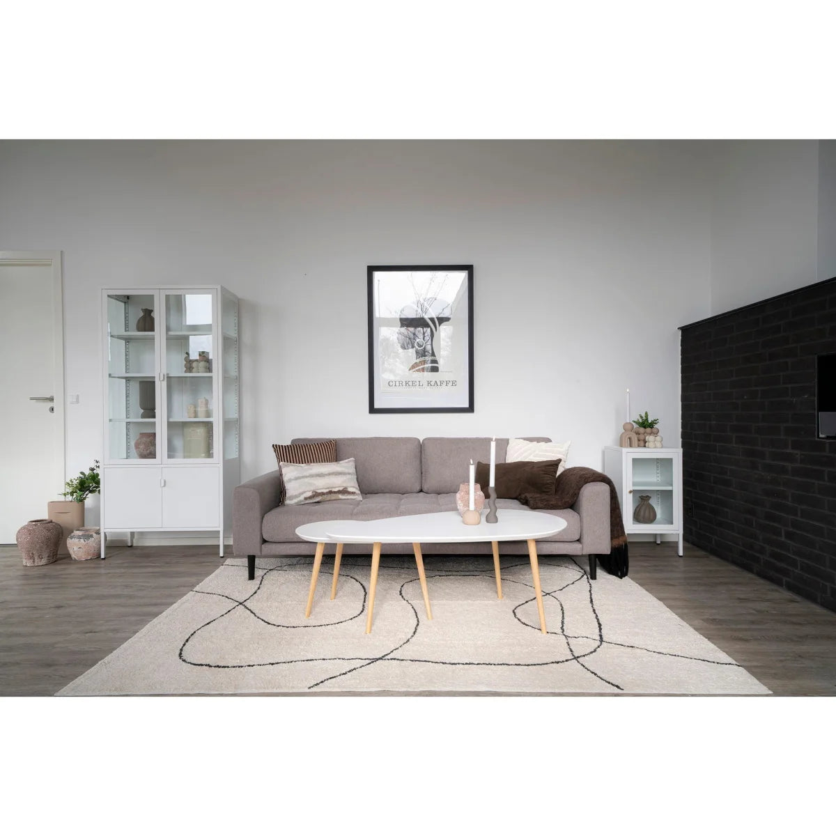 Canapé gris à pieds en bois et coussins décoratifs, tapis coton imprimé noir et blanc 160x230 cm