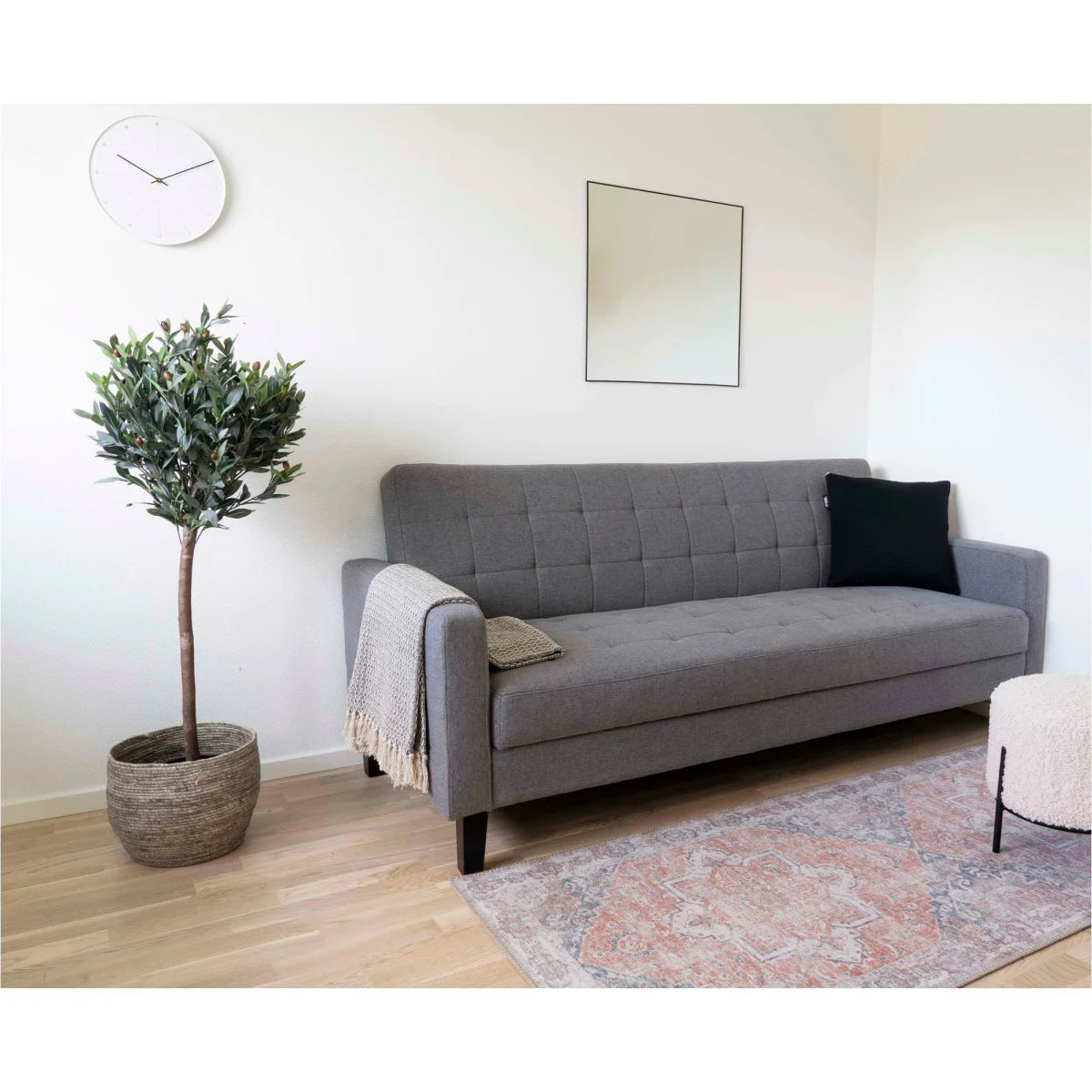 Canapé en tissu gris capitonné, pieds noirs, couverture texturée