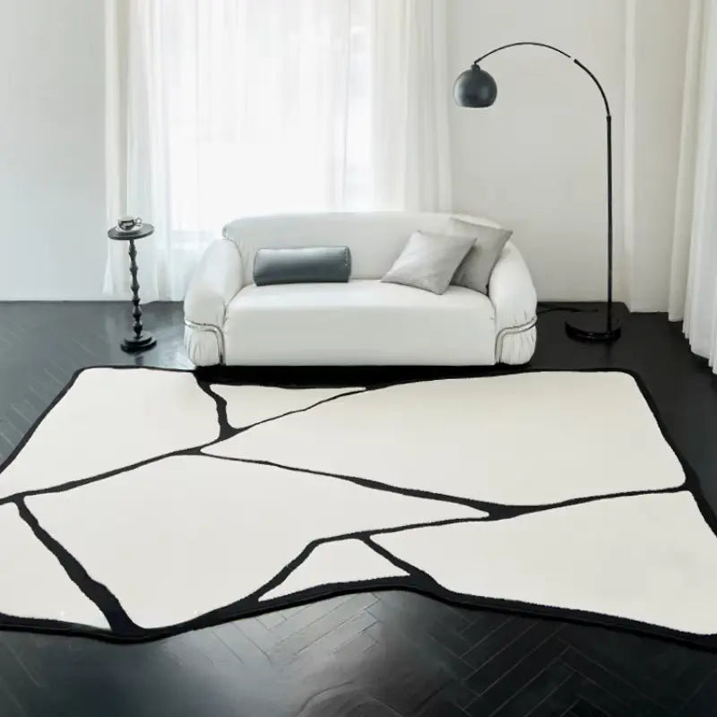 Tapis forme asymétrique noir et blanc dans un salon moderne avec canapé blanc et parquet sombre.