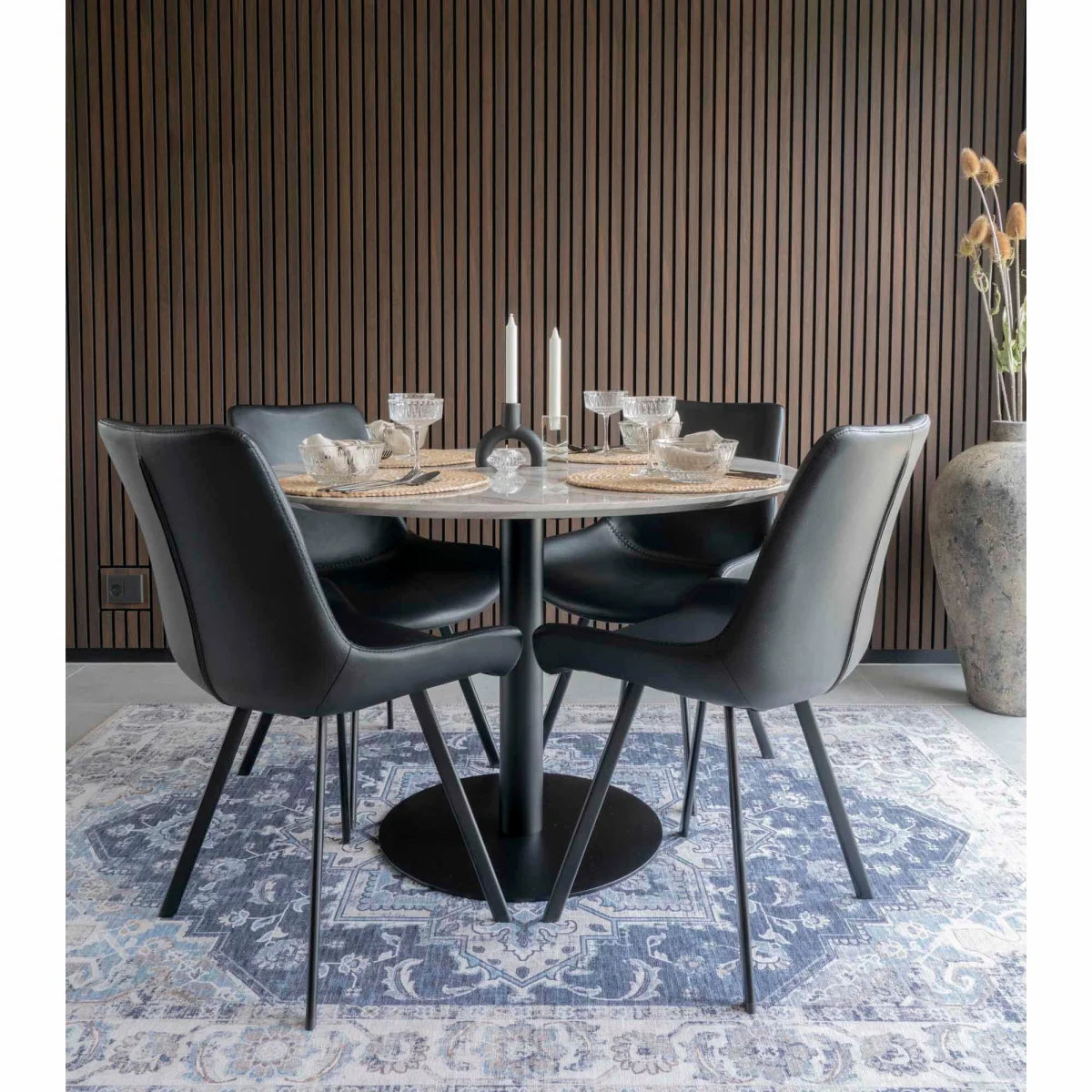 Chaises de salle à manger en cuir noir et métal autour d’une table ronde