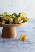 Plateau à gâteau en teck avec baies dorées et husks sur la table
