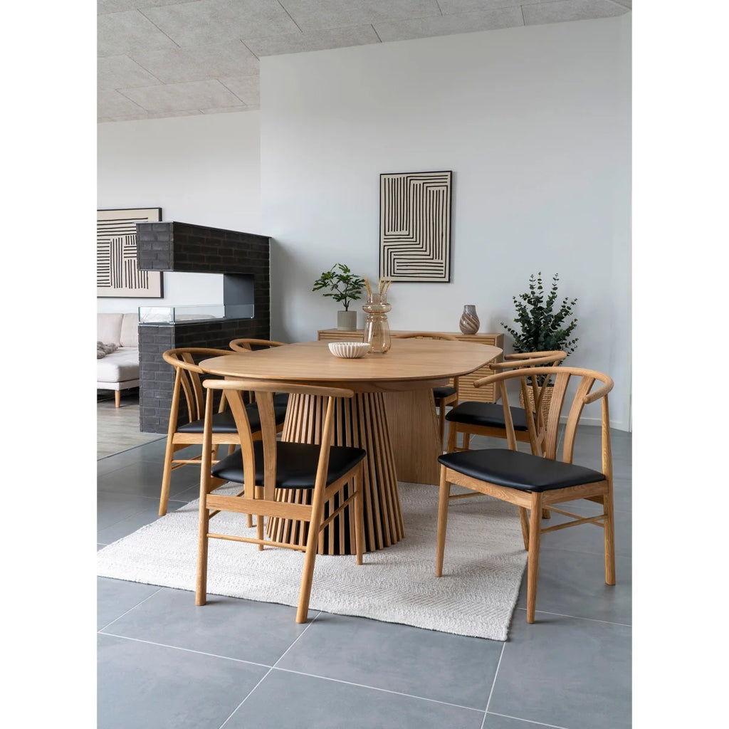 Table à manger en bois clair avec base cannelée, chaises tapissées noires