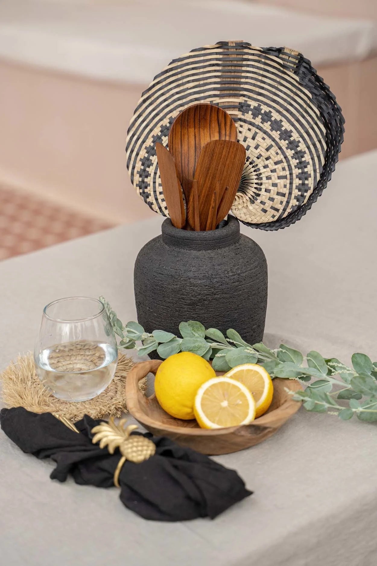 Vase en terre cuite noir à texture côtelée tenant des ustensiles en bois et un trivet tissé