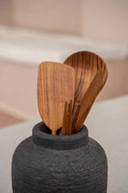 Vase en terre cuite noir texturé avec ustensiles de cuisine en bois