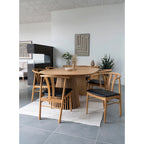 Table à manger en bois clair avec base festonnée et chaises rembourrées noires